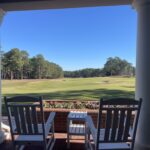 Two rocking chairs on porch overlooking golf course.