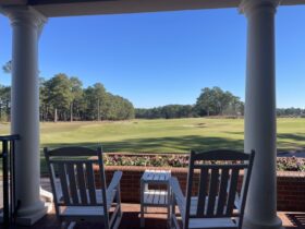 Two rocking chairs on porch overlooking golf course.