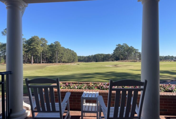 Two rocking chairs on porch overlooking golf course.
